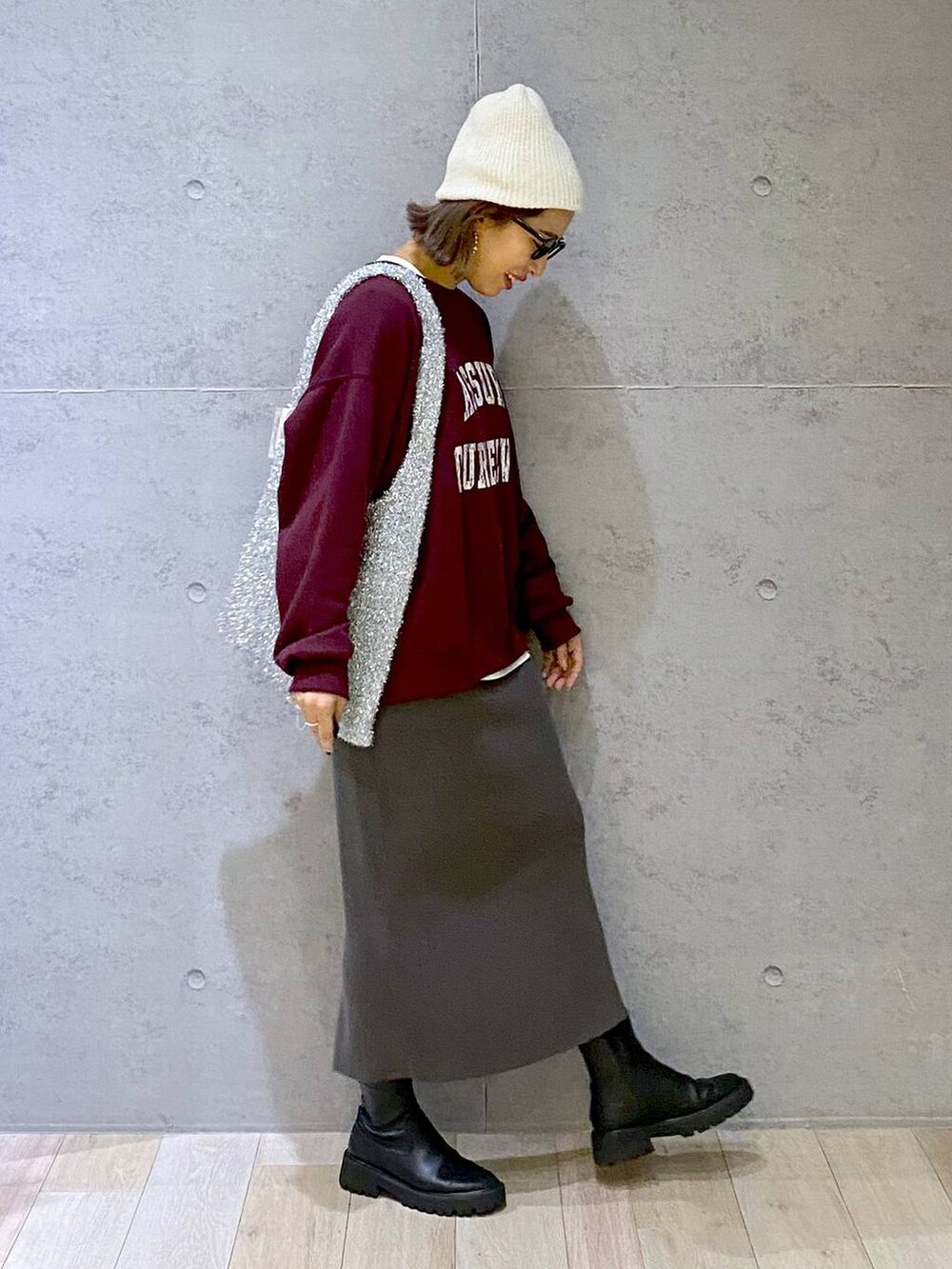 グレー系のスカート、ブラック系のブーツ、レッド系のスウェットを着用したレディースの秋コーディネートの4枚目の写真