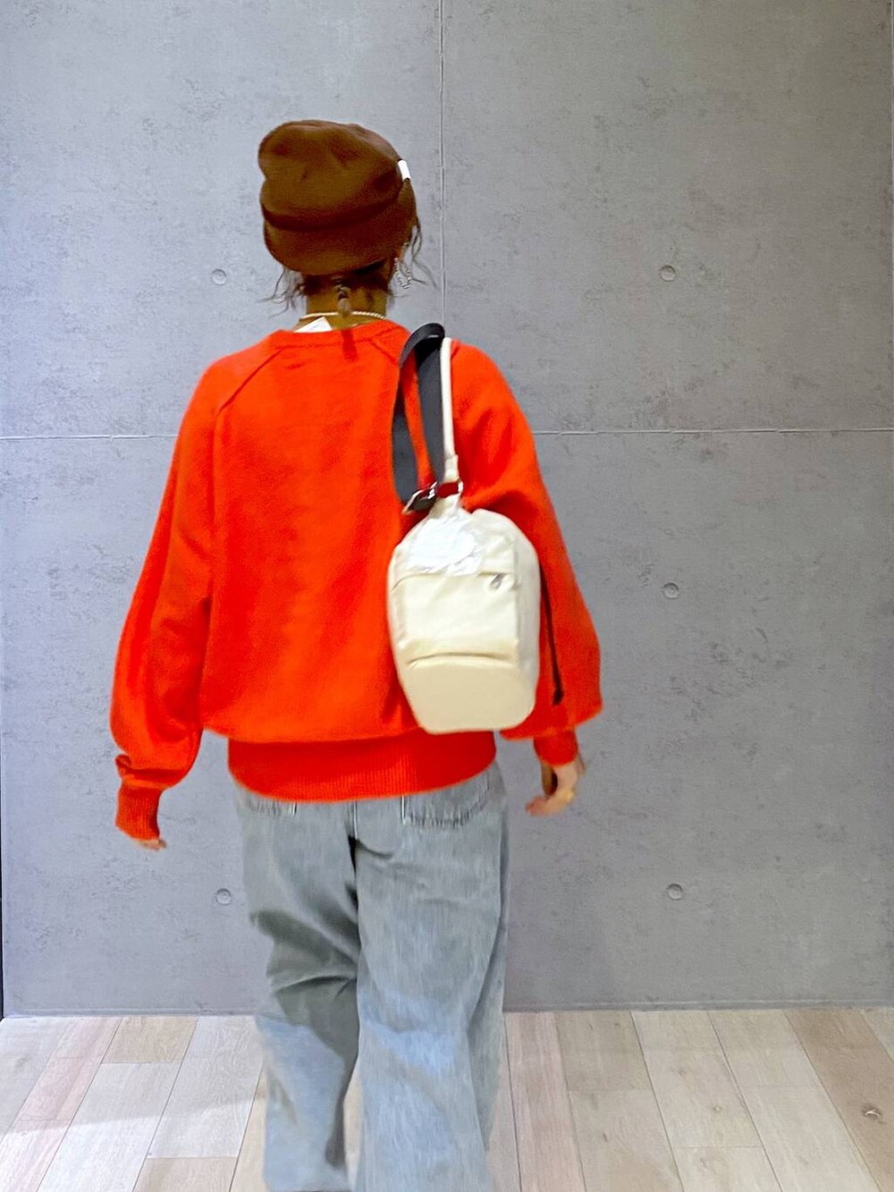 ホワイト系のショルダーバッグ、ブルー系のデニムパンツ、レッド系のニット/セーターを着用したレディースの秋コーディネートの5枚目の写真