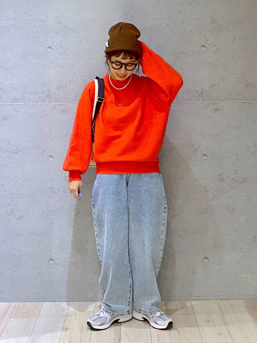 ホワイト系のショルダーバッグ、ブルー系のデニムパンツ、レッド系のニット/セーターを着用したレディースの秋コーディネートの2枚目の写真