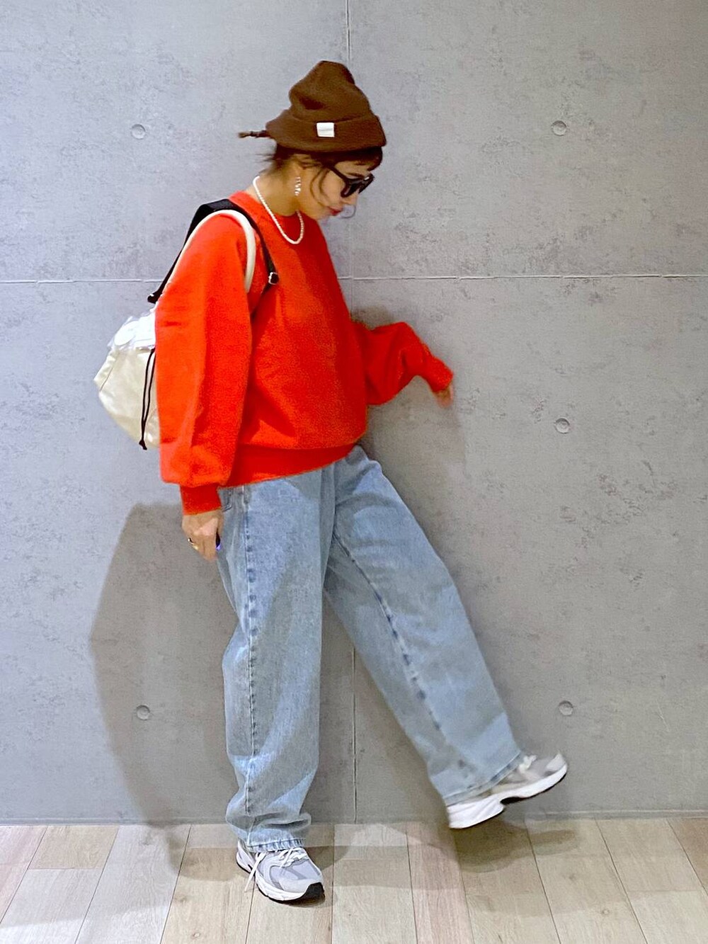 ホワイト系のショルダーバッグ、ブルー系のデニムパンツ、レッド系のニット/セーターを着用したレディースの秋コーディネートの3枚目の写真