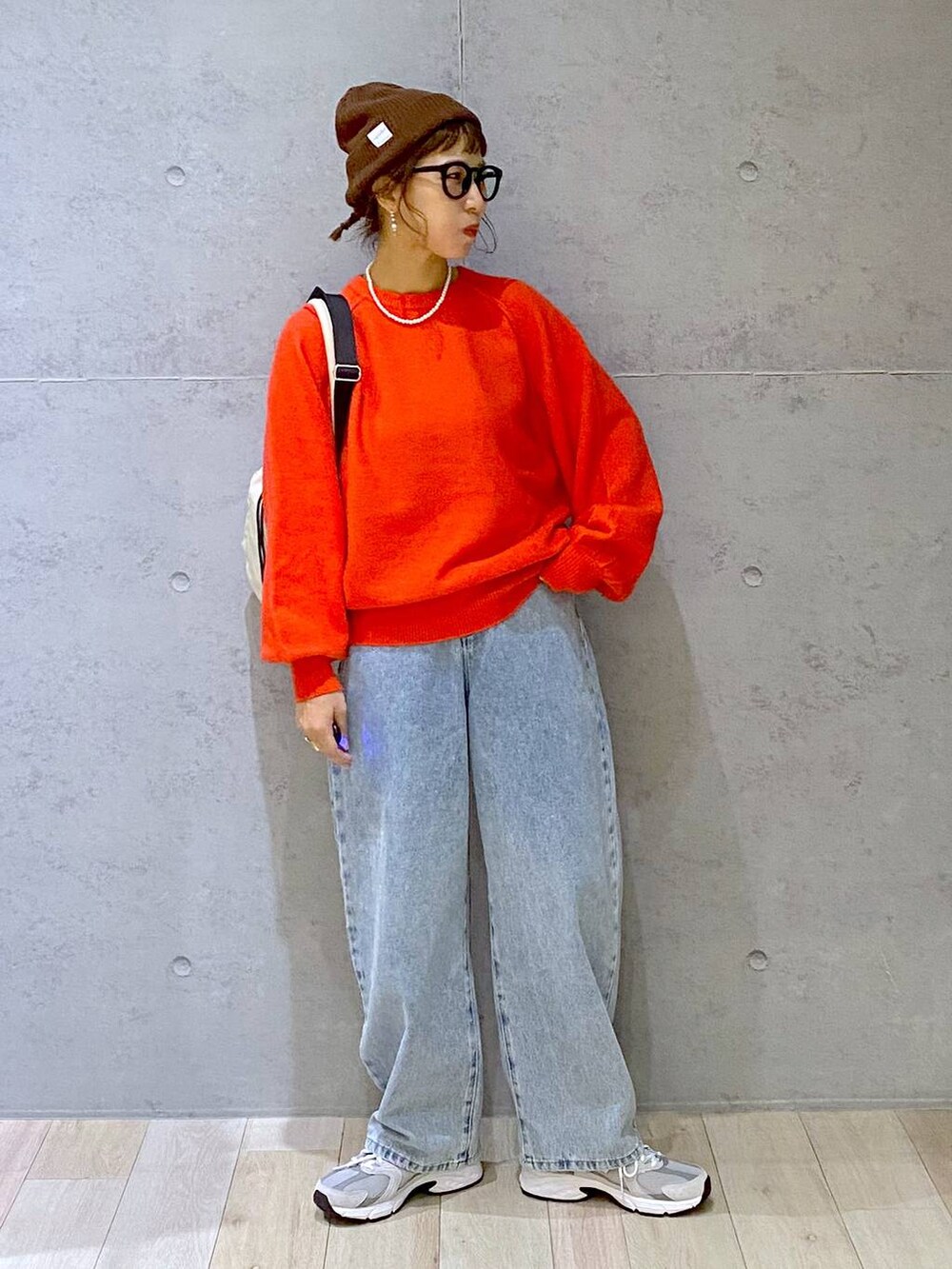 ホワイト系のショルダーバッグ、ブルー系のデニムパンツ、レッド系のニット/セーターを着用したレディースの秋コーディネートの6枚目の写真
