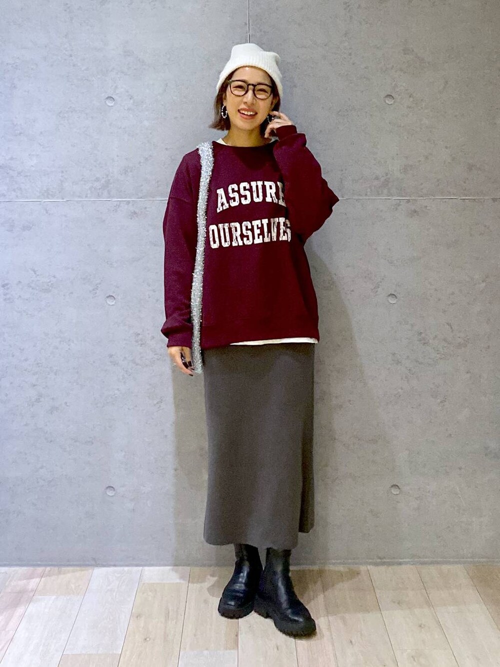 グレー系のスカート、ブラック系のブーツ、レッド系のスウェットを着用したレディースの秋コーディネートの6枚目の写真