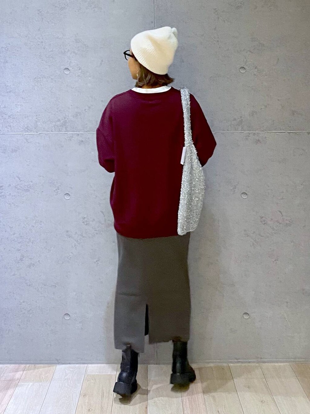 グレー系のスカート、ブラック系のブーツ、レッド系のスウェットを着用したレディースの秋コーディネートの3枚目の写真