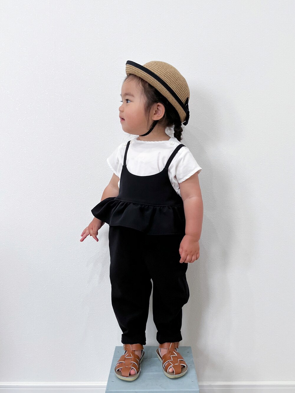 ブラック系のオールインワン・サロペット、ホワイト系のTシャツ/カットソー、ブラウン系のサンダルを着用したキッズの夏コーディネートの3枚目の写真