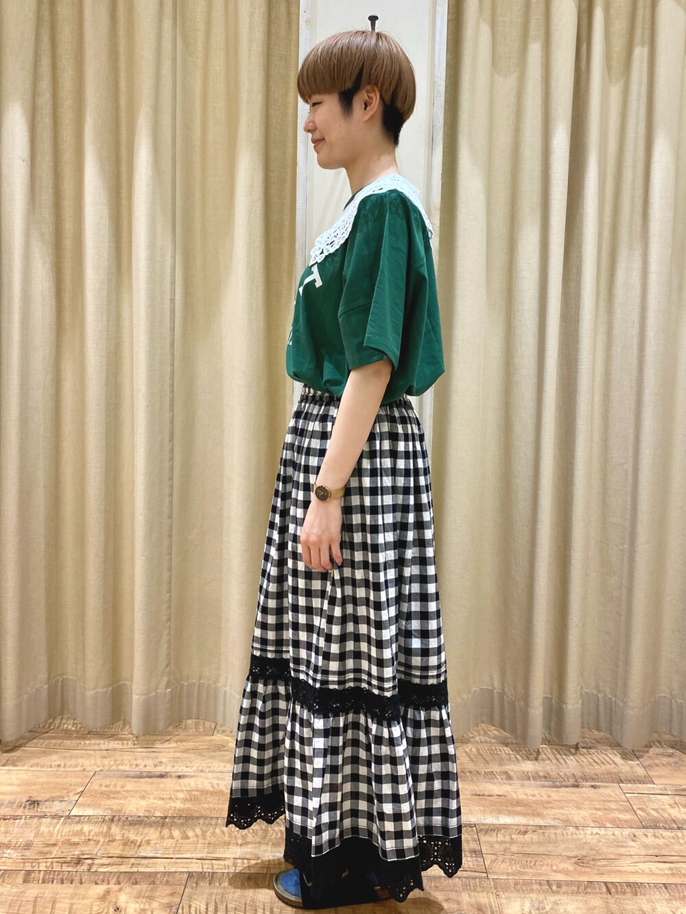 ブラック系のスカート、グリーン系のTシャツ/カットソー、ホワイト系のハンドバッグを着用したレディースの春コーディネートの2枚目の写真