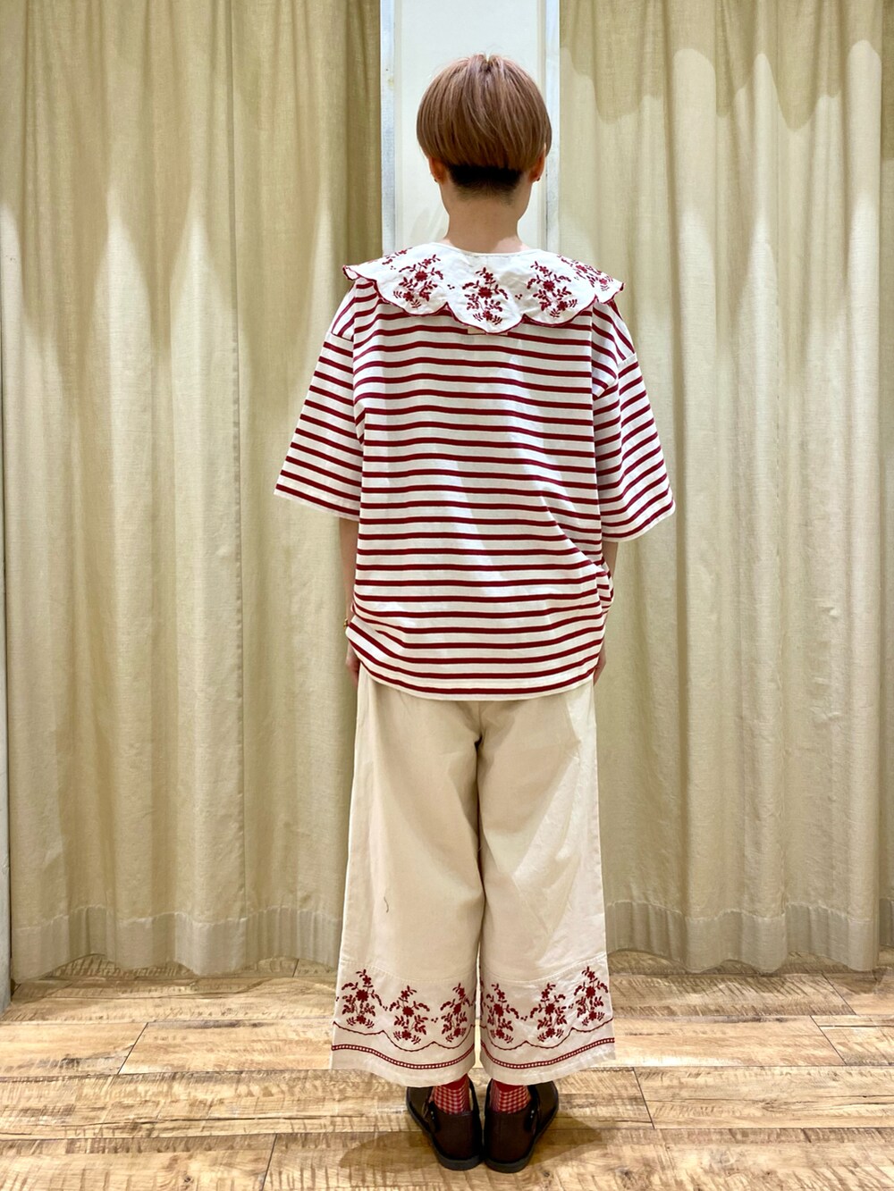 レッド系のTシャツ/カットソー、ホワイト系のその他パンツ、ブラウン系のハンドバッグを着用したレディースの春コーディネートの2枚目の写真