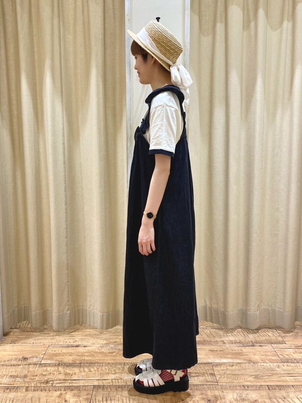 ブラック系のワンピース、ホワイト系のTシャツ/カットソー、ホワイト系のサンダルを着用したレディースの春コーディネートの2枚目の写真