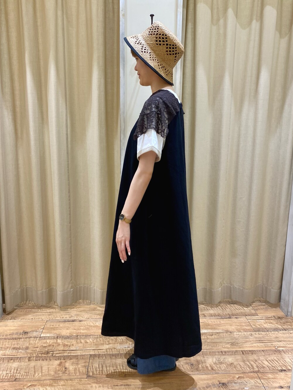 ブラック系のワンピース、ブルー系のデニムパンツ、ブラック系のハンドバッグを着用したレディースの春コーディネートの2枚目の写真