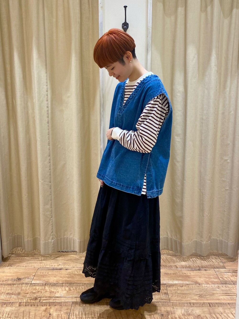 ブルー系のベスト、ブラック系のスカート、ホワイト系のTシャツ/カットソーを着用したレディースの冬コーディネートの2枚目の写真