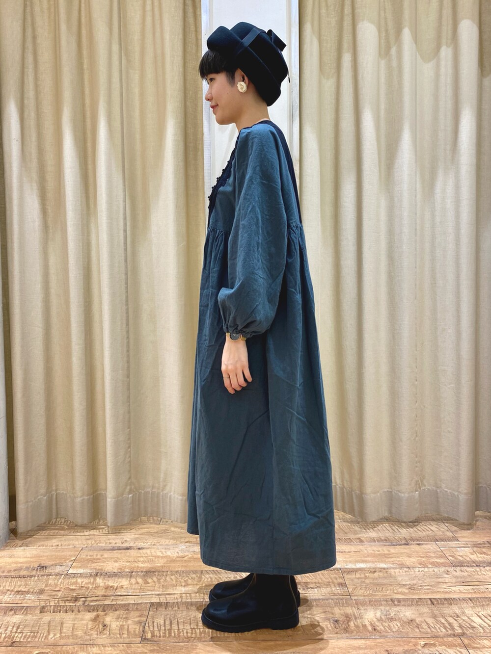 グリーン系のワンピース/ドレス、ブラック系のブーツ、ブラック系のハットを着用したレディースの秋コーディネートの2枚目の写真