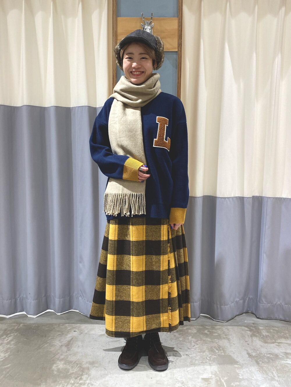 ブルー系のニット/セーター、イエロー系のスカート、ベージュ系のブーツを着用したレディースの秋コーディネートの2枚目の写真