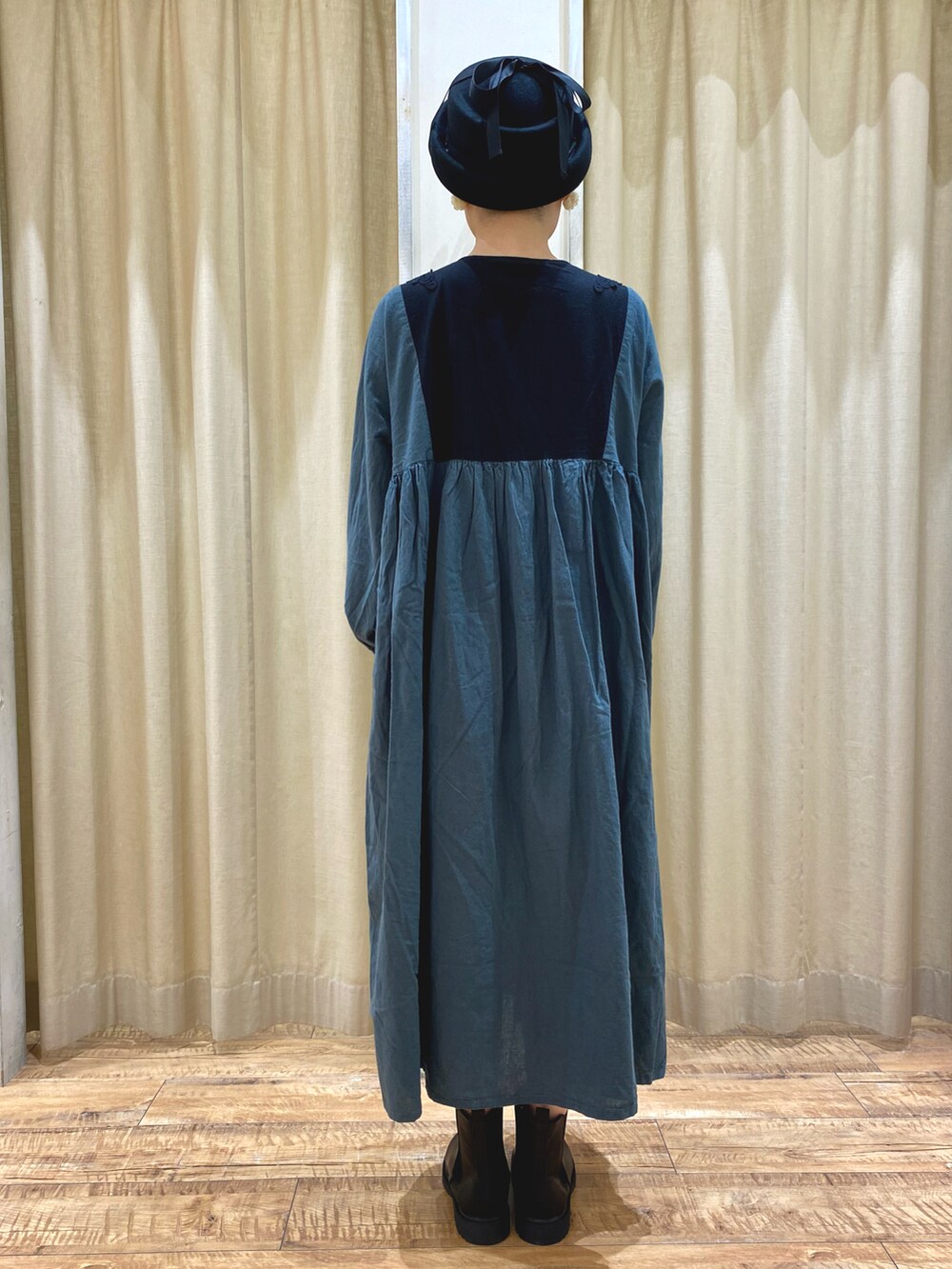 グリーン系のワンピース/ドレス、ブラック系のブーツ、ブラック系のハットを着用したレディースの秋コーディネートの4枚目の写真