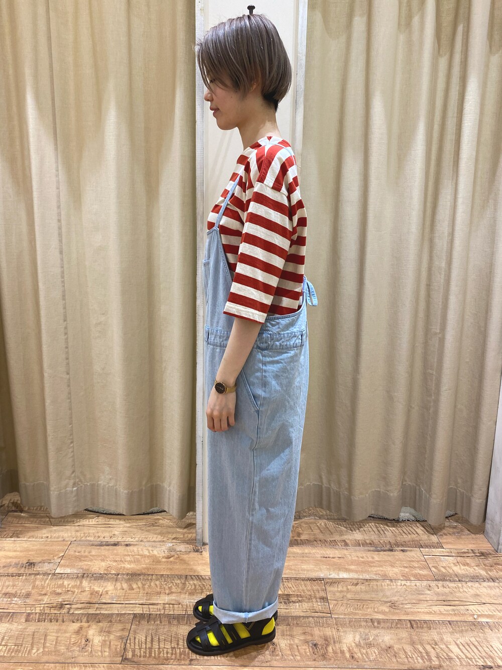 レッド系のTシャツ/カットソー、ブルー系のサロペット/オーバーオール、ブラウン系のサンダルを着用したレディースの春コーディネートの2枚目の写真