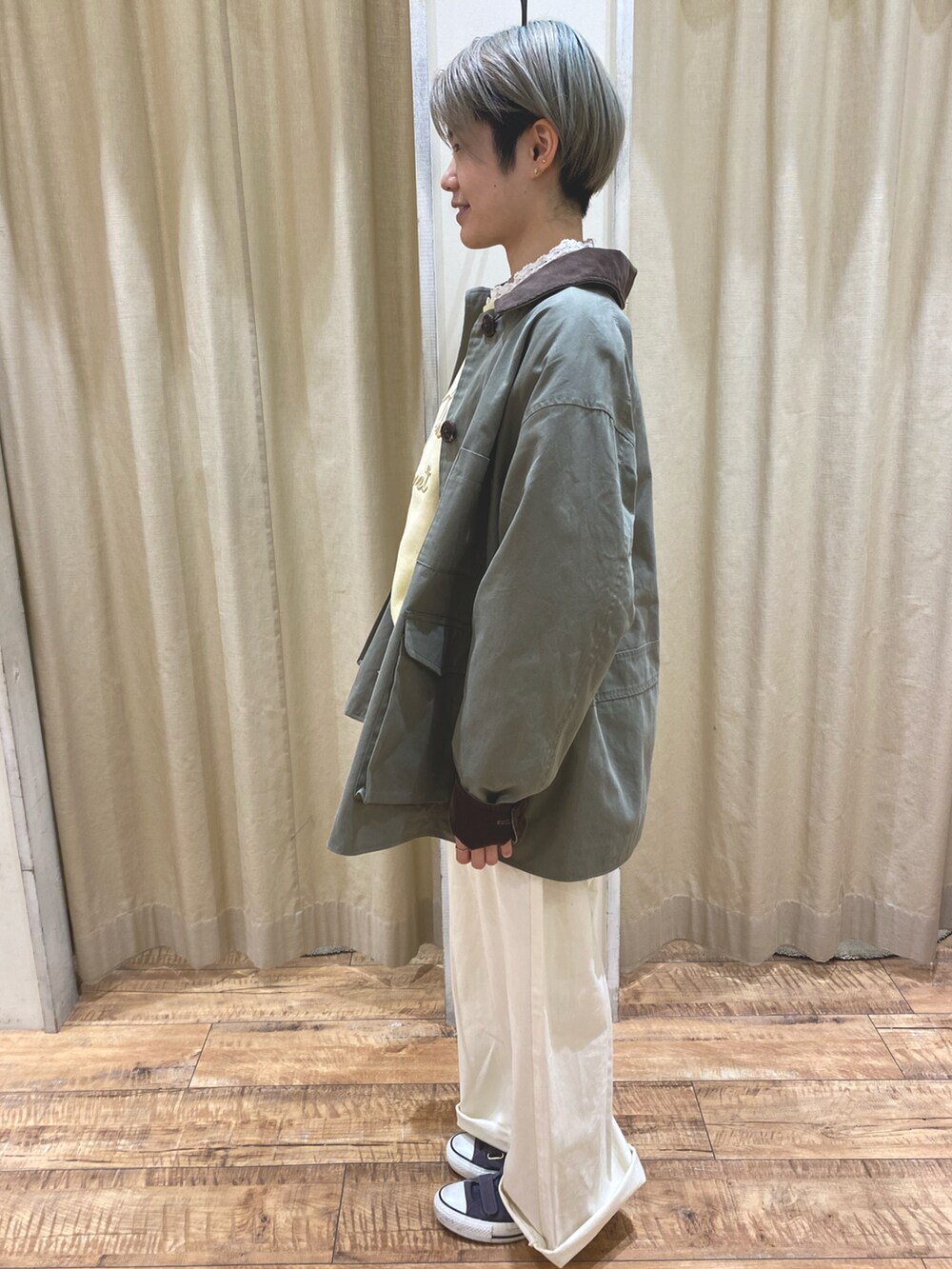 イエロー系のスウェット、グリーン系のブルゾン、ホワイト系のシャツ/ブラウスを着用したレディースの冬コーディネートの2枚目の写真