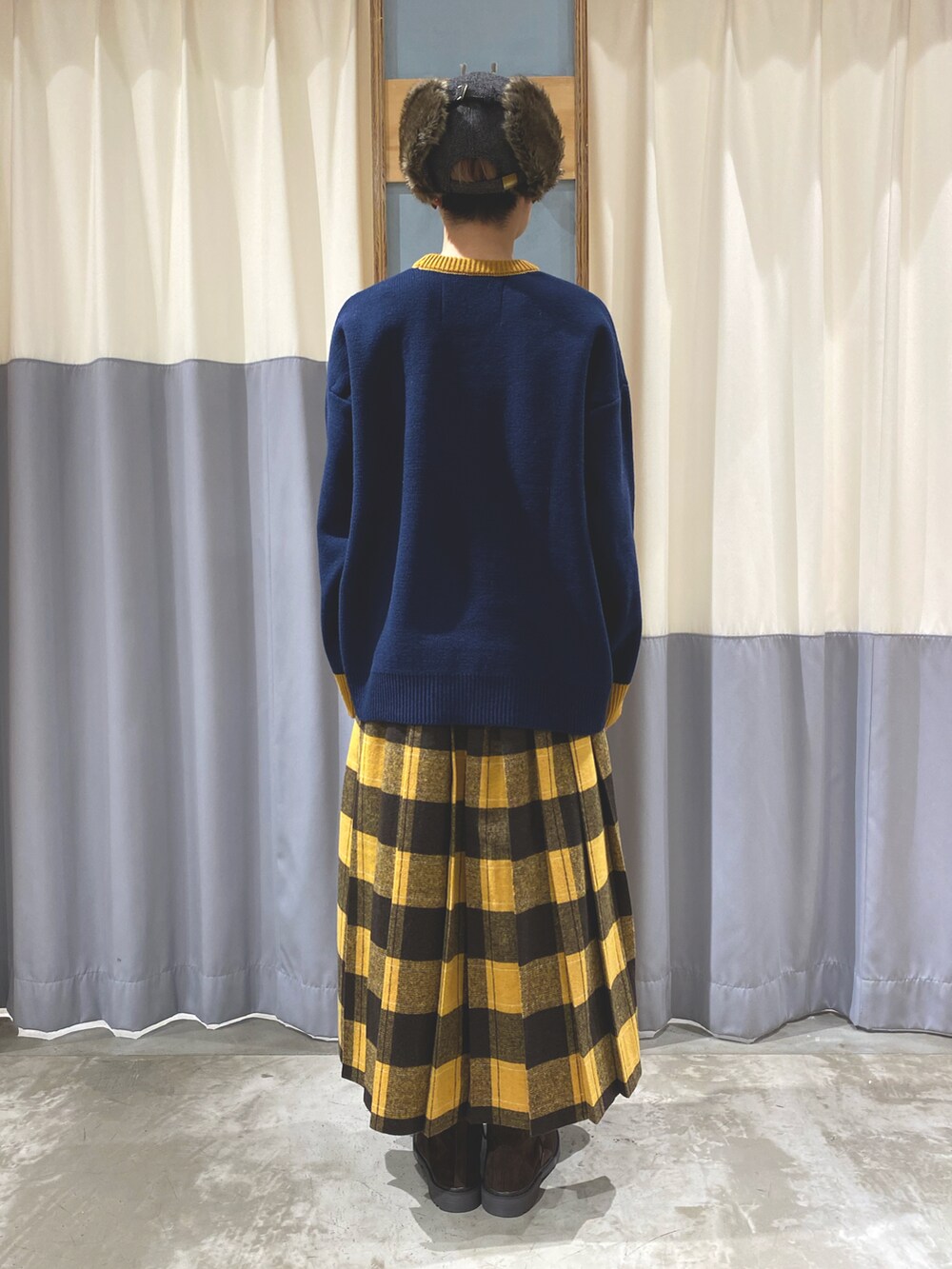 ブルー系のニット/セーター、イエロー系のスカート、ベージュ系のブーツを着用したレディースの秋コーディネートの4枚目の写真