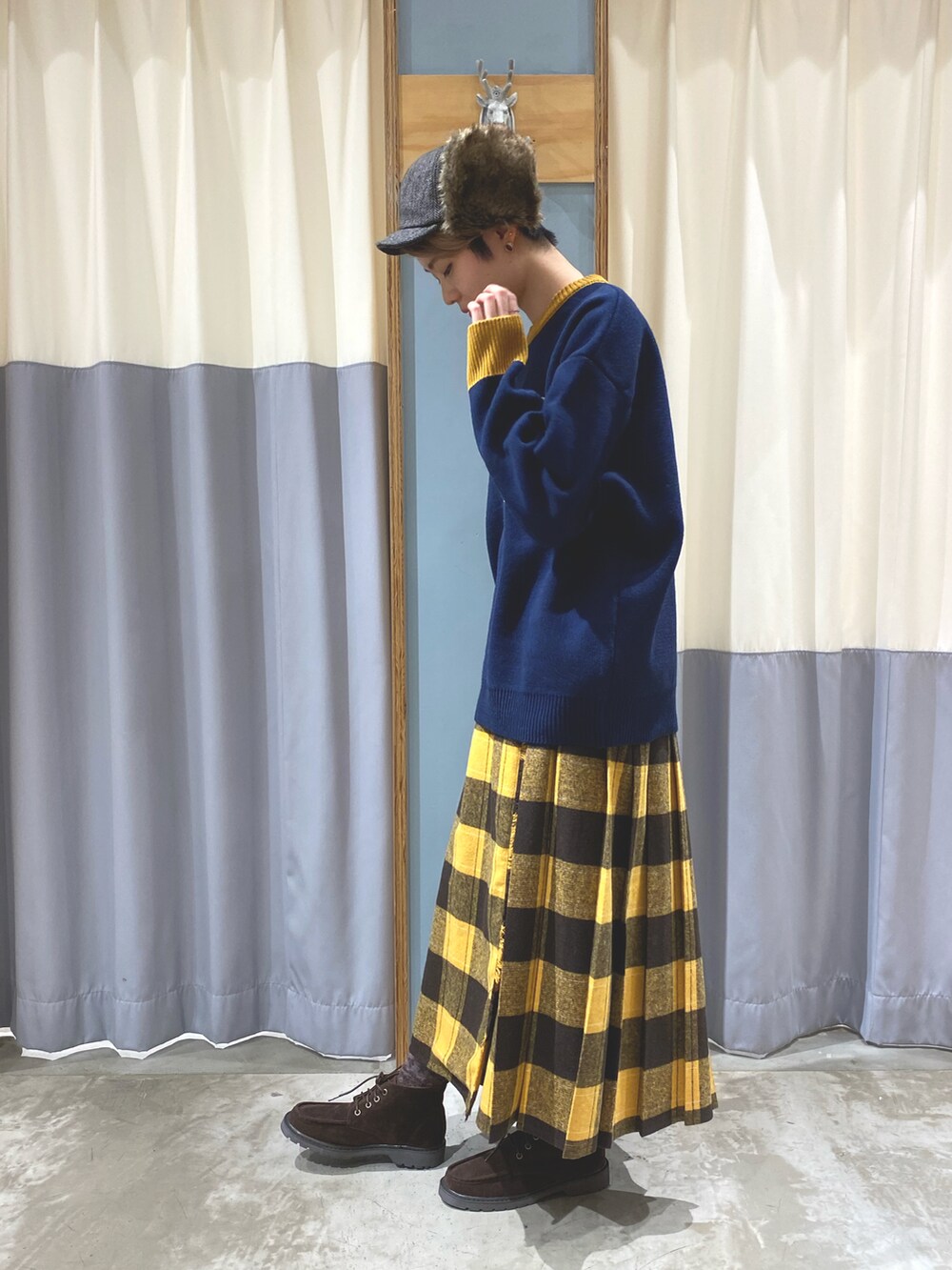 ブルー系のニット/セーター、イエロー系のスカート、ベージュ系のブーツを着用したレディースの秋コーディネートの3枚目の写真