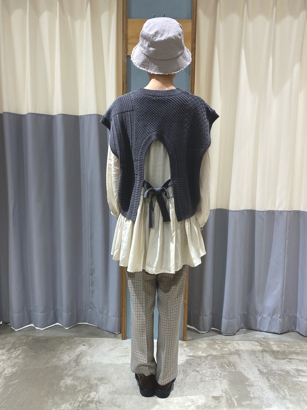 グレー系のベスト、ホワイト系のシャツ/ブラウス、ブラウン系のその他パンツを着用したレディースの秋コーディネートの2枚目の写真