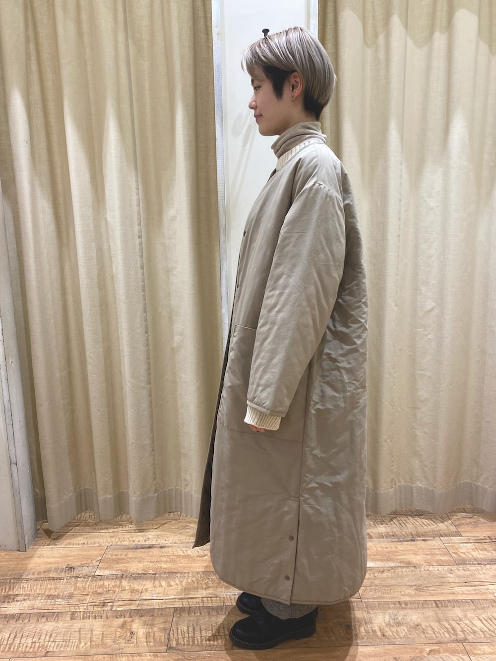 ベージュ系のノーカラーコート、ブラック系のニット/セーター、ブラック系のその他パンツを着用したレディースの冬コーディネートの2枚目の写真