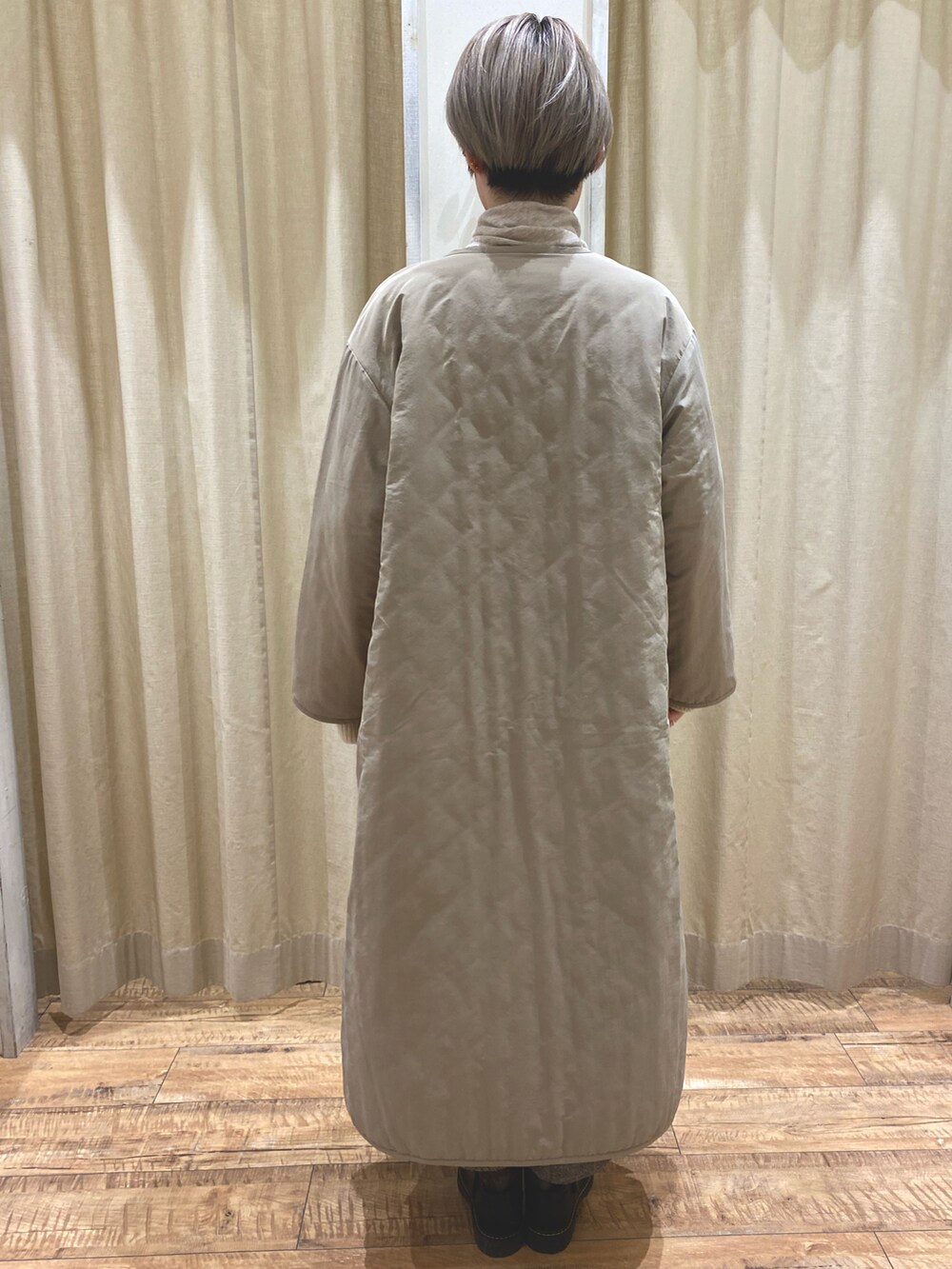 ベージュ系のノーカラーコート、ブラック系のニット/セーター、ブラック系のその他パンツを着用したレディースの冬コーディネートの3枚目の写真