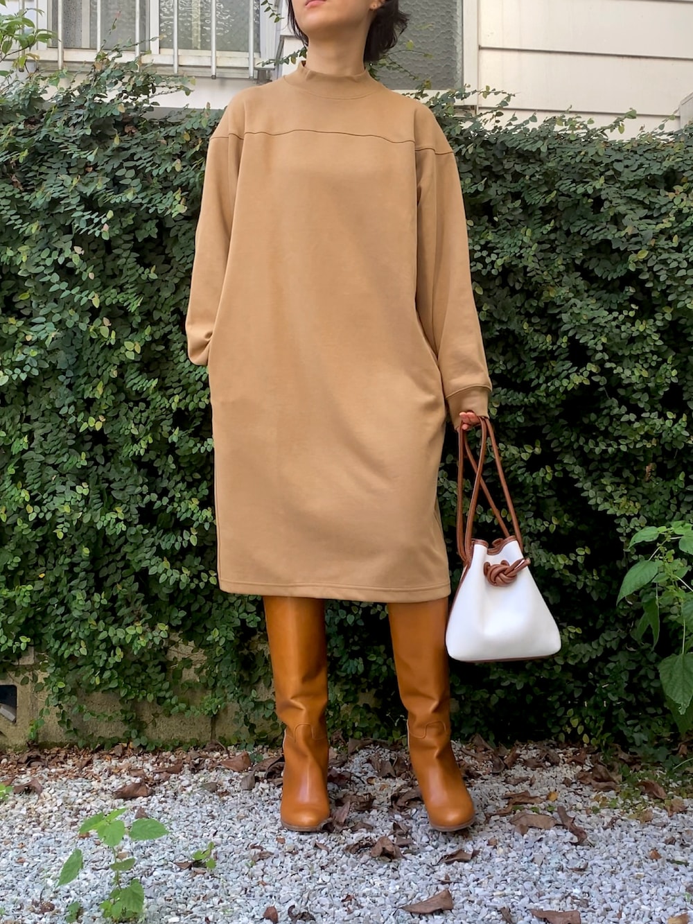 ベージュ系のワンピース、ブラウン系のブーツ、ホワイト系のハンドバッグを着用したレディースの秋コーディネートの3枚目の写真