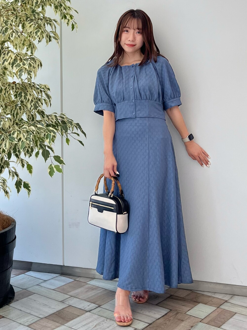 ブルー系のスカート、ブルー系のTシャツ/カットソー、ベージュ系のハンドバッグを着用したレディースの夏コーディネートの2枚目の写真