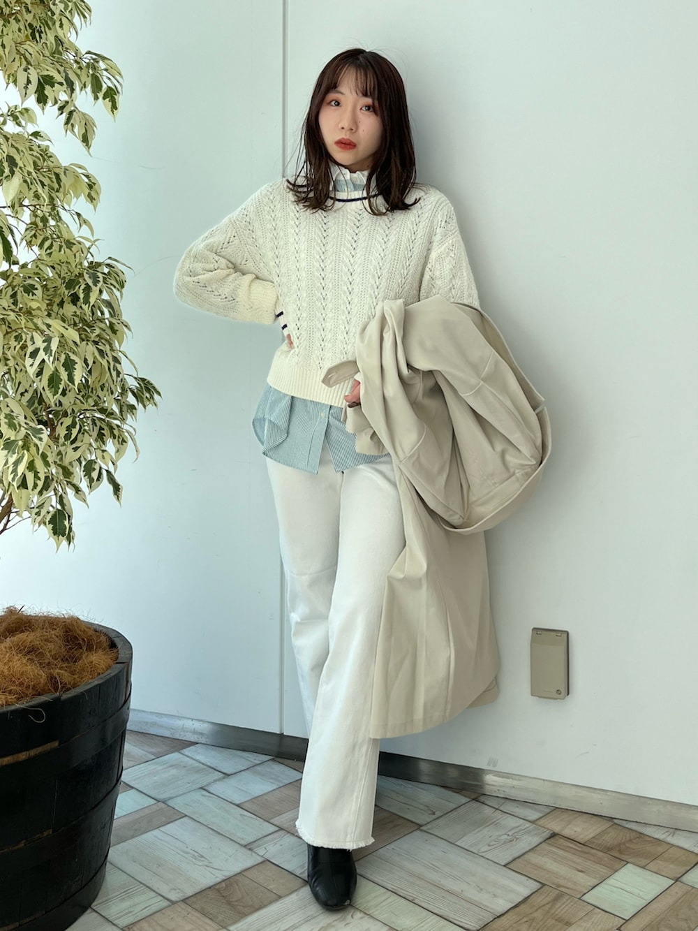 ベージュ系のトレンチコート、ホワイト系のニット/セーター、ホワイト系のデニムパンツを着用したレディースの冬コーディネートの2枚目の写真