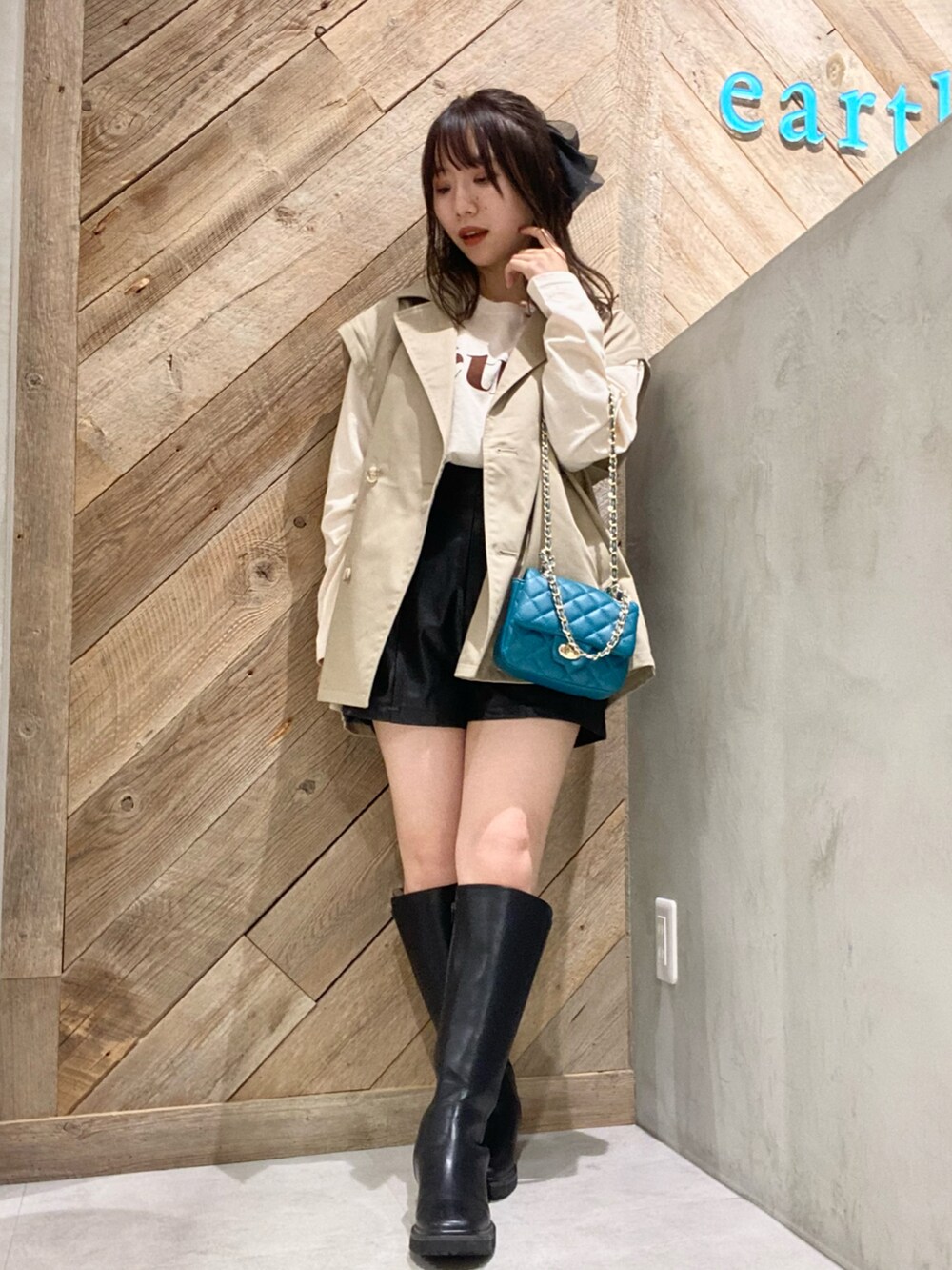 ブルー系のショルダーバッグ、ベージュ系のトレンチコートを着用したレディースの秋コーディネートの2枚目の写真