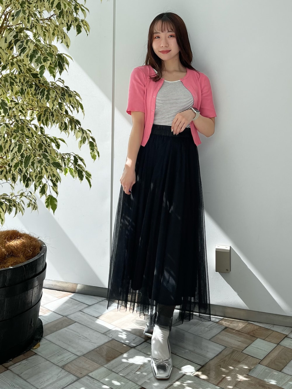 ブラック系のスカート、ピンク系のTシャツ/カットソー、シルバー系のシューズを着用したレディースの春コーディネートの2枚目の写真