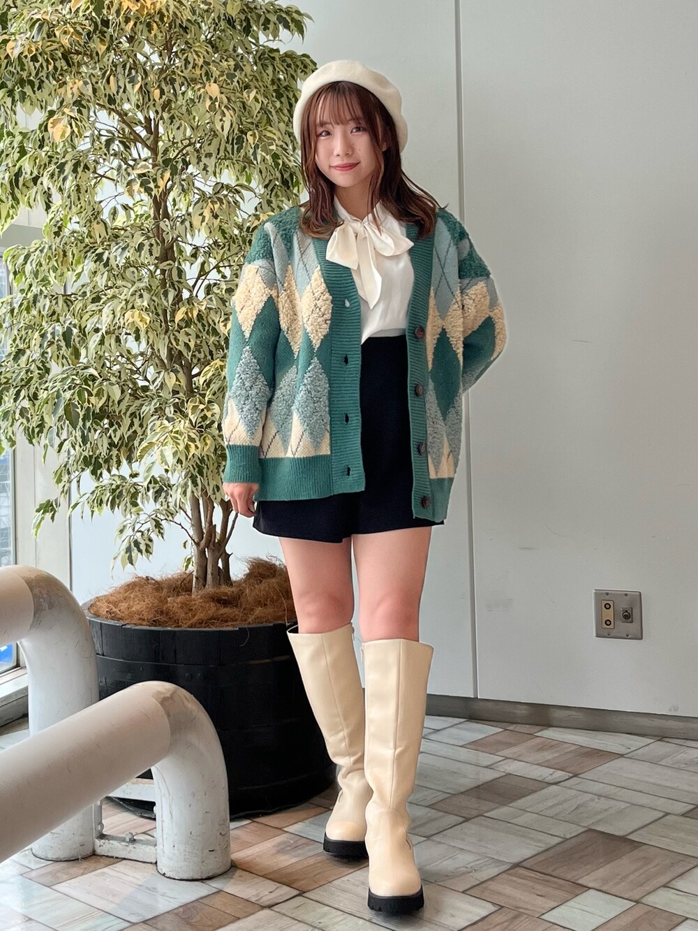 グリーン系のカーディガン/ボレロ、ホワイト系のシャツ/ブラウス、ホワイト系のブーツを着用したレディースの秋コーディネートの3枚目の写真