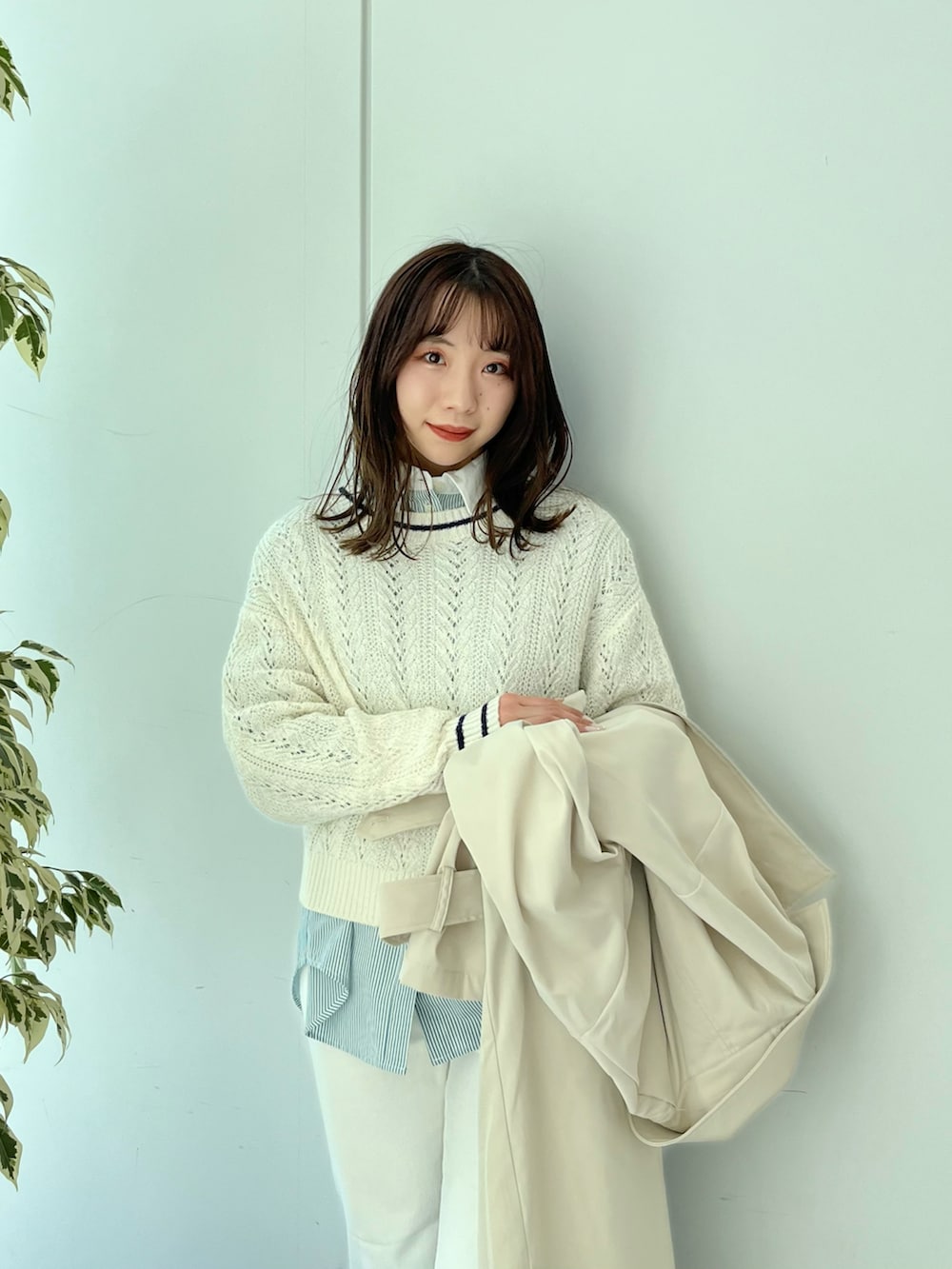 ベージュ系のトレンチコート、ホワイト系のニット/セーター、ホワイト系のデニムパンツを着用したレディースの冬コーディネートの3枚目の写真