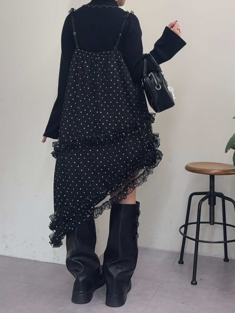 ホワイト系のチュニック、ブラック系のショルダーバッグ、ブラウン系のブーツを着用したレディースの冬コーディネートの2枚目の写真