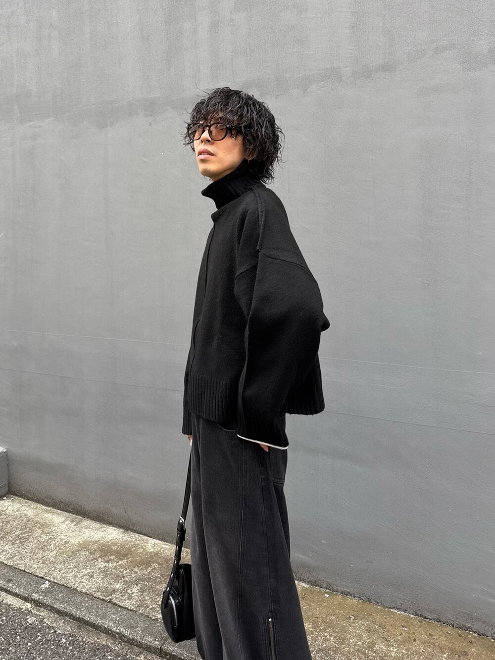 ブラック系のショルダーバッグ、ブラック系のニット/セーター、ブラック系のデニムパンツを着用したメンズの秋コーディネートの4枚目の写真