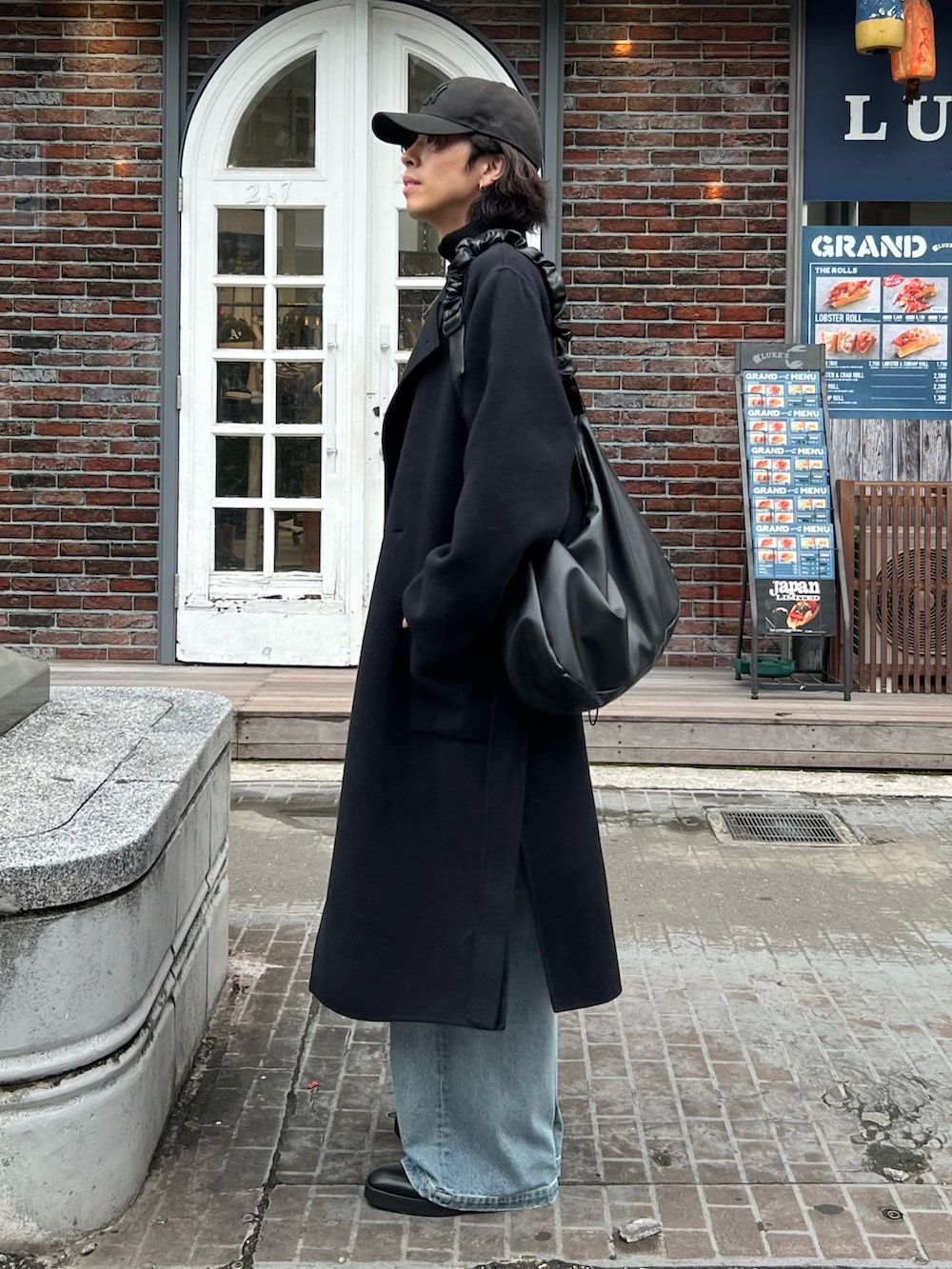 ブラック系のニット/セーター、ブラック系のショルダーバッグ、ブラック系のその他アウターを着用したメンズの秋コーディネートの2枚目の写真