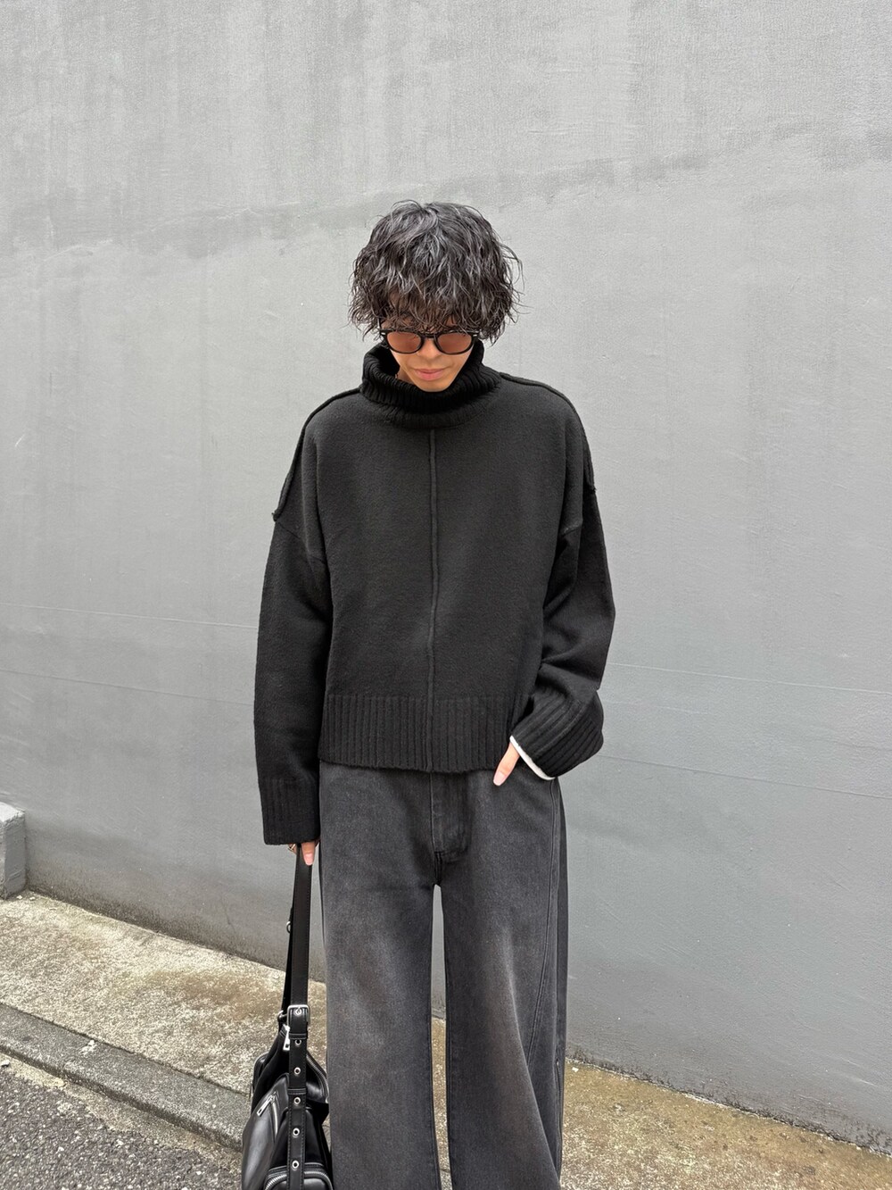 ブラック系のショルダーバッグ、ブラック系のニット/セーター、ブラック系のデニムパンツを着用したメンズの秋コーディネートの3枚目の写真