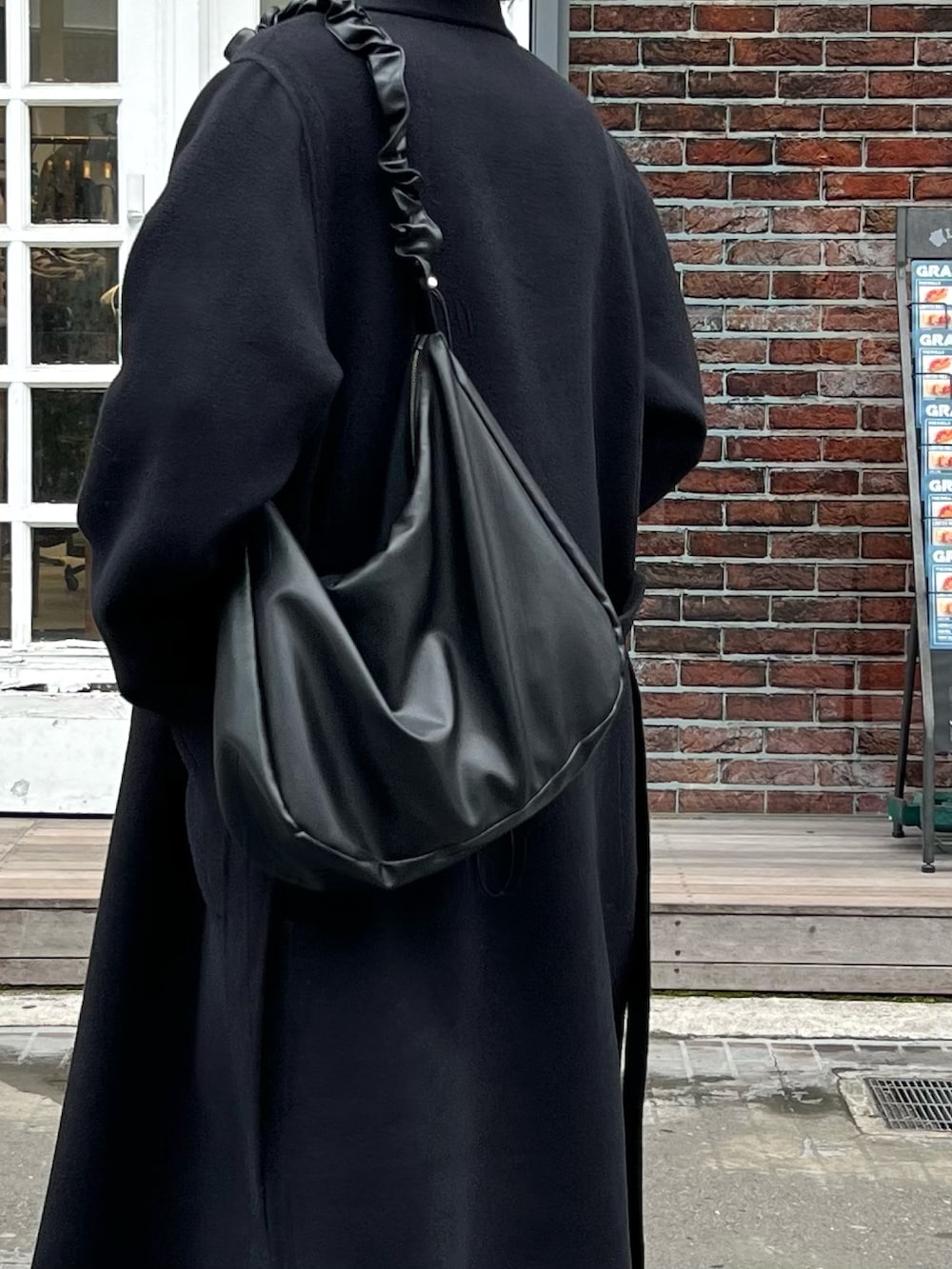 ブラック系のニット/セーター、ブラック系のショルダーバッグ、ブラック系のその他アウターを着用したメンズの秋コーディネートの4枚目の写真