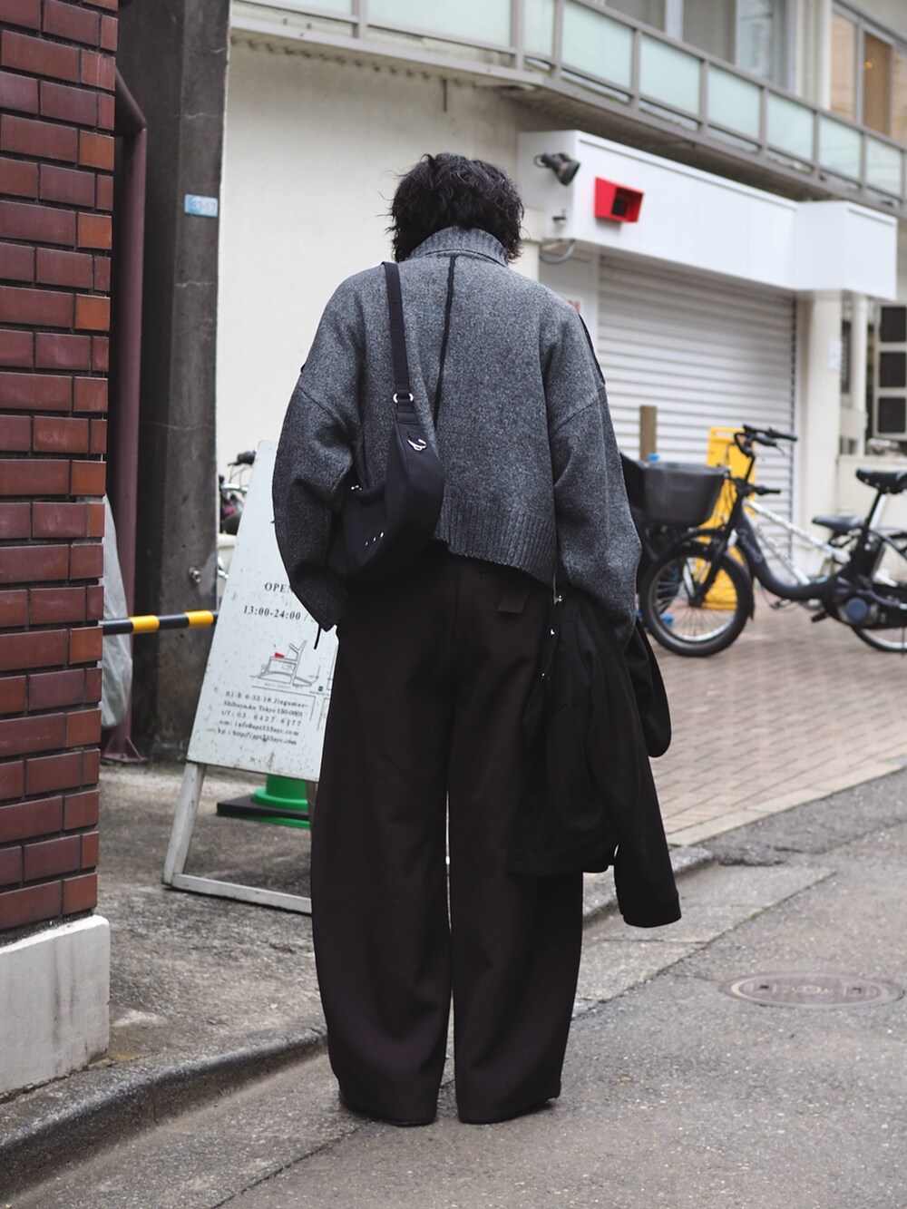 ブラック系のショルダーバッグ、グレー系のニット/セーター、グレー系のスラックスを着用したメンズの冬コーディネートの2枚目の写真