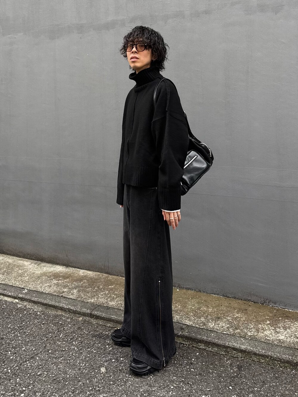 ブラック系のショルダーバッグ、ブラック系のニット/セーター、ブラック系のデニムパンツを着用したメンズの秋コーディネートの2枚目の写真