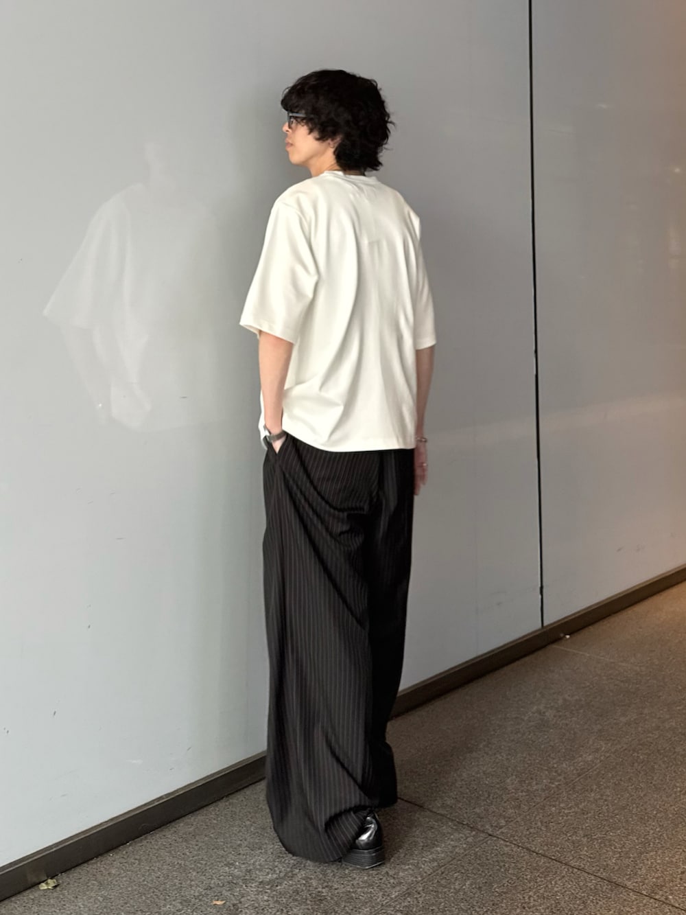 ホワイト系のTシャツ/カットソー、ブラック系のスラックス、シルバー系のネックレスを着用したメンズの夏コーディネートの3枚目の写真