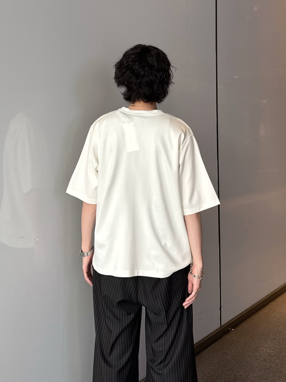 ホワイト系のTシャツ/カットソー、ブラック系のスラックス、シルバー系のネックレスを着用したメンズの夏コーディネートの7枚目の写真