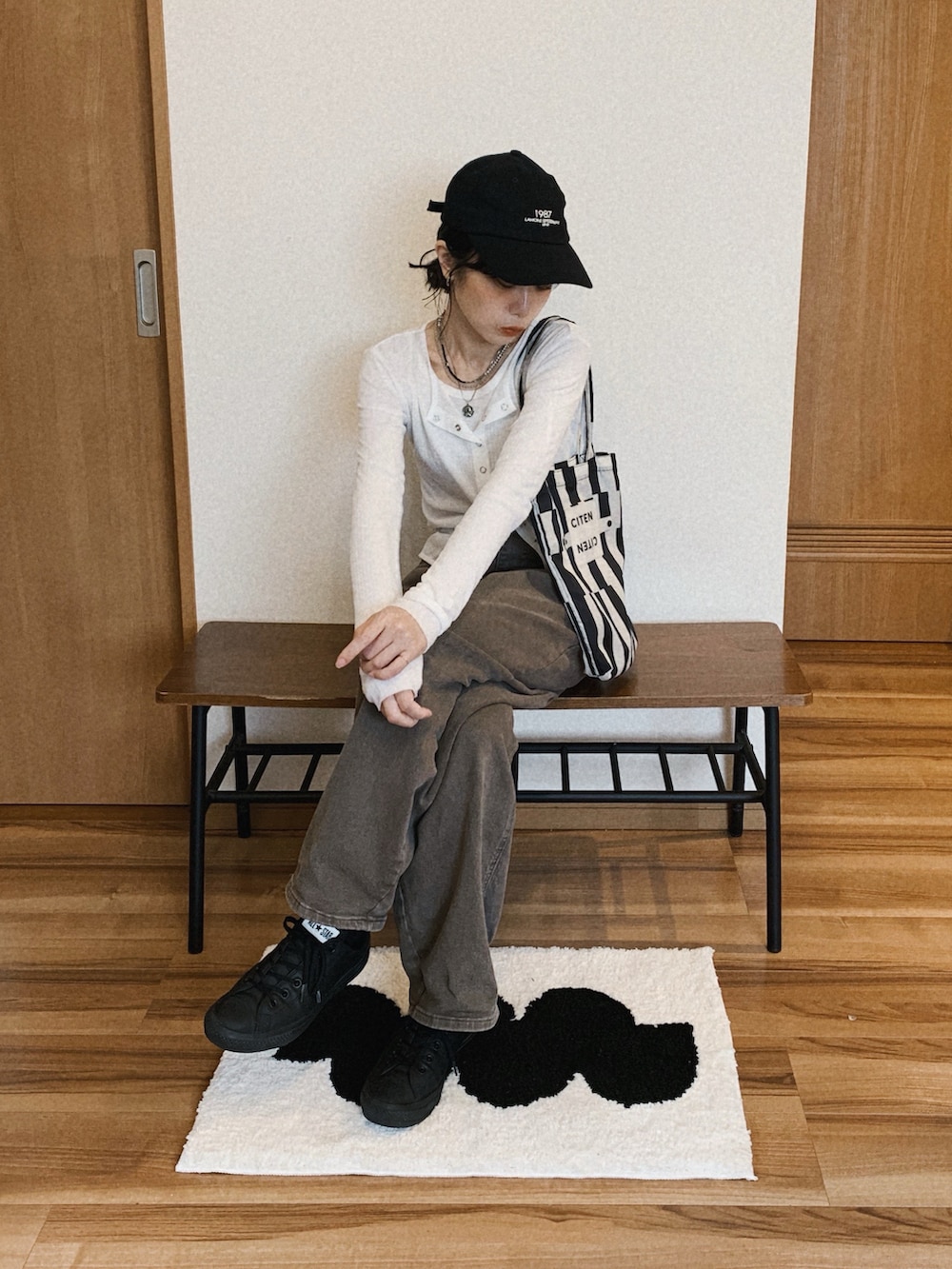 ブラウン系のデニムパンツ、ホワイト系のカーディガン/ボレロ、ブラック系のエコバッグ/サブバッグを着用したレディースの春コーディネートの2枚目の写真
