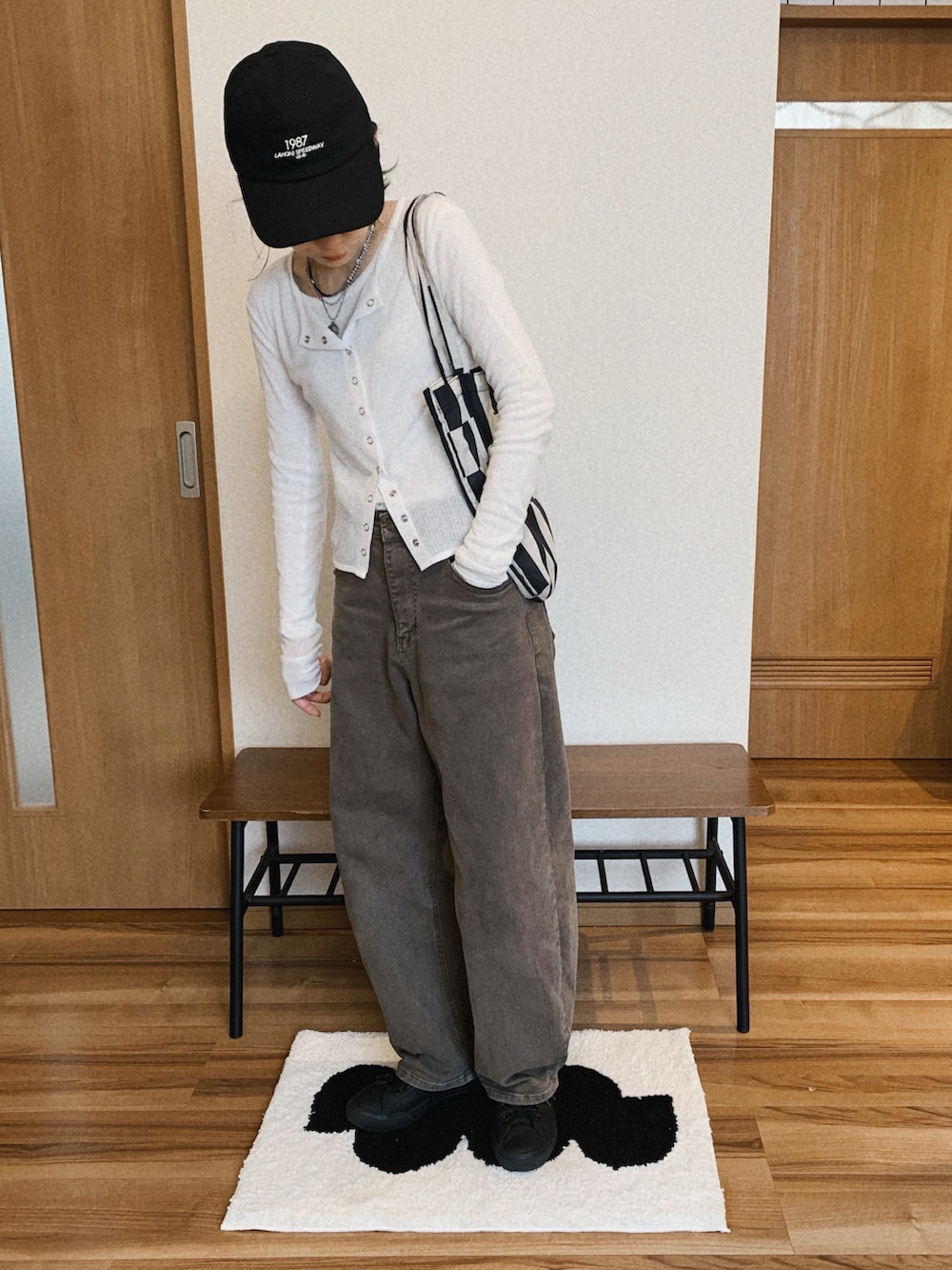 ブラウン系のデニムパンツ、ホワイト系のカーディガン/ボレロ、ブラック系のエコバッグ/サブバッグを着用したレディースの春コーディネートの3枚目の写真