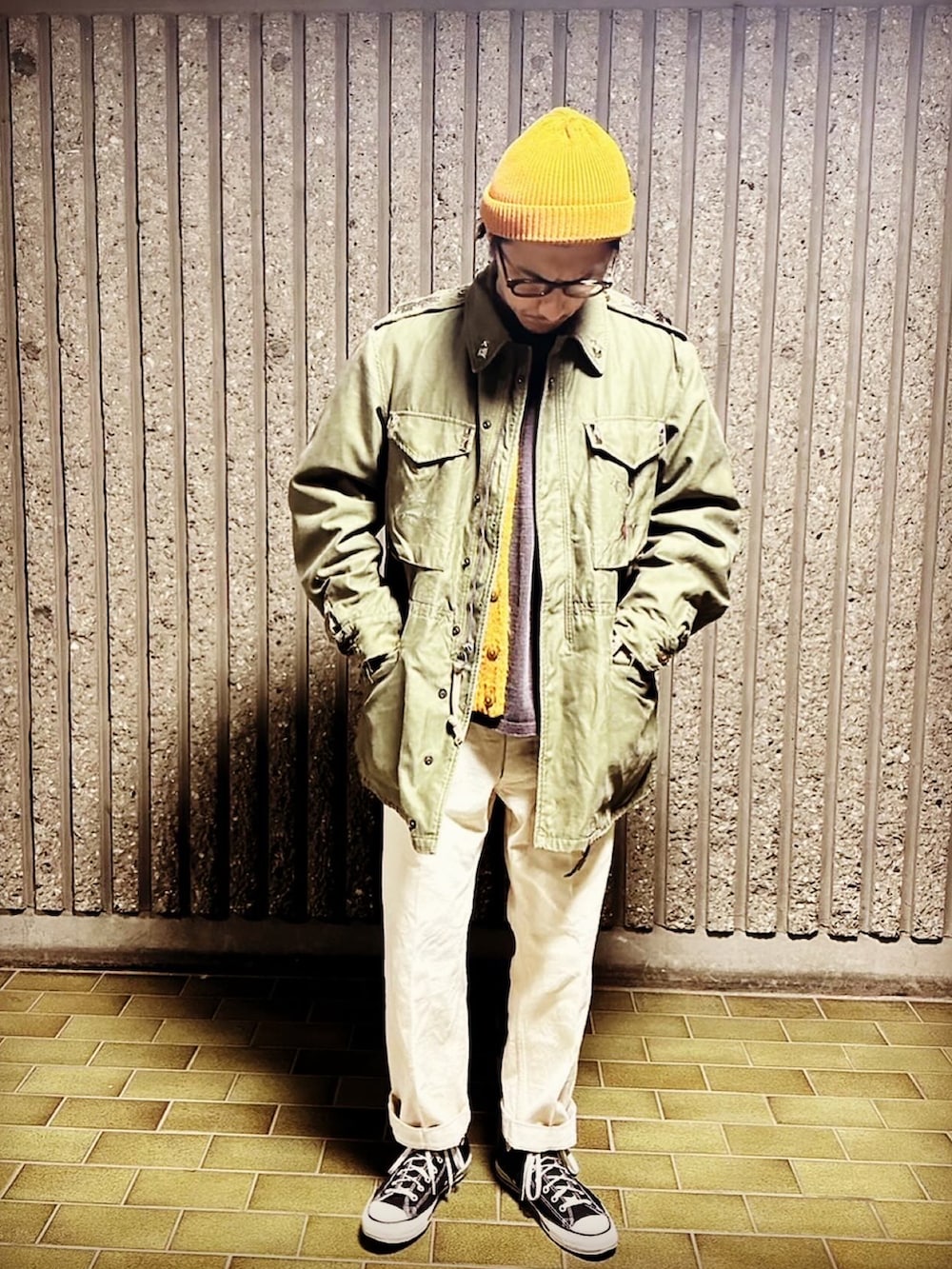 グリーン系のミリタリージャケット、ベージュ系のチノパンツ、ブラック系のスニーカーを着用したメンズの冬コーディネートの4枚目の写真