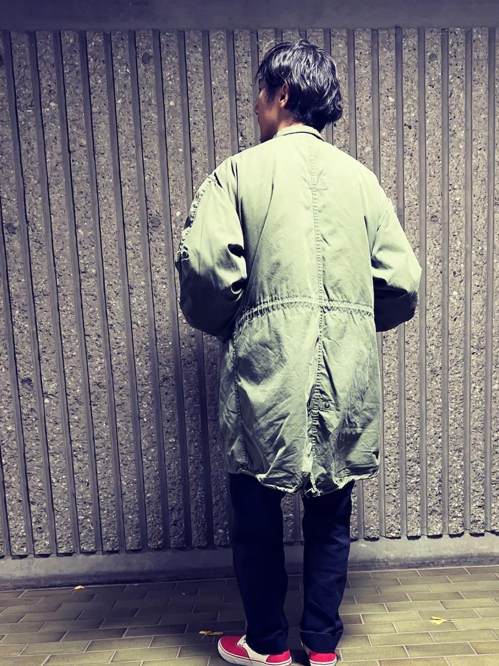 グリーン系のモッズコート、ブラック系のカーディガン/ボレロ、ブラック系のチノパンツを着用したメンズの冬コーディネートの2枚目の写真