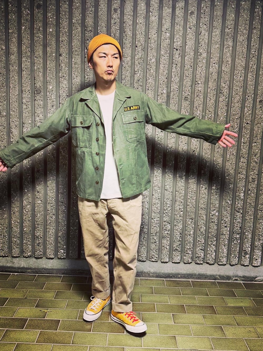 グリーン系のミリタリージャケット、ホワイト系のトップス、グリーン系のチノパンツを着用したメンズの秋コーディネートの4枚目の写真
