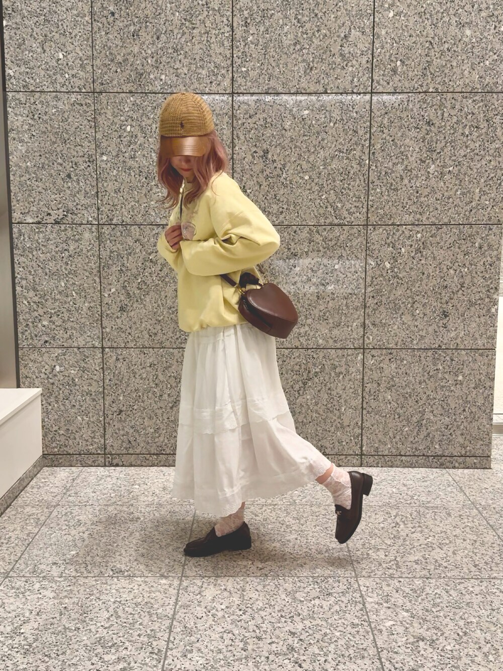 イエロー系のパーカー、ホワイト系のスカート、ブラウン系のローファーを着用したレディースの秋コーディネートの2枚目の写真