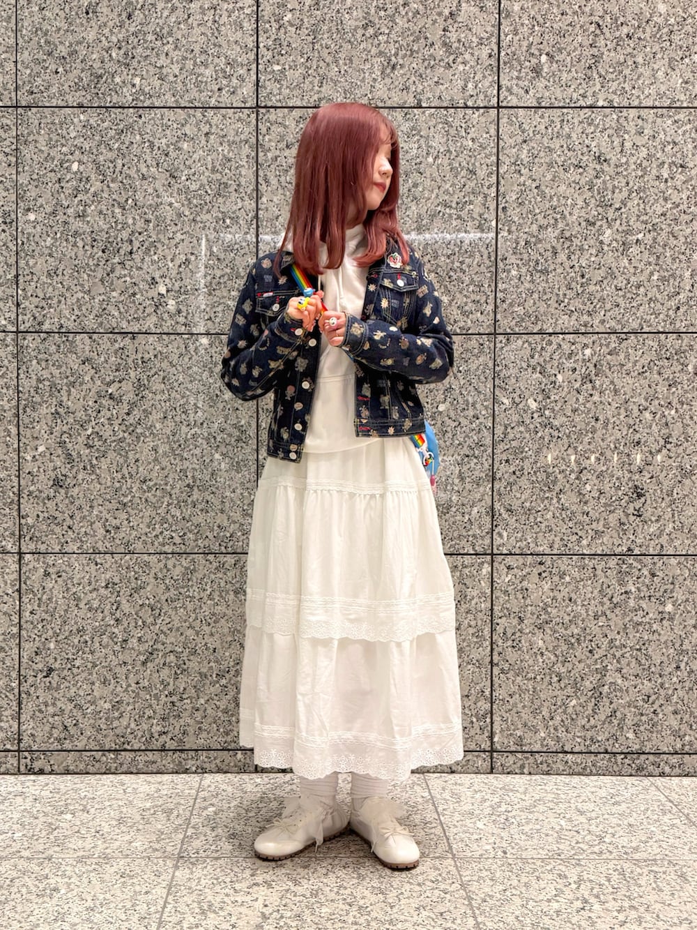 ブルー系のデニムジャケット、ブルー系のショルダーバッグ、ホワイト系のスカートを着用したレディースの春コーディネートの2枚目の写真