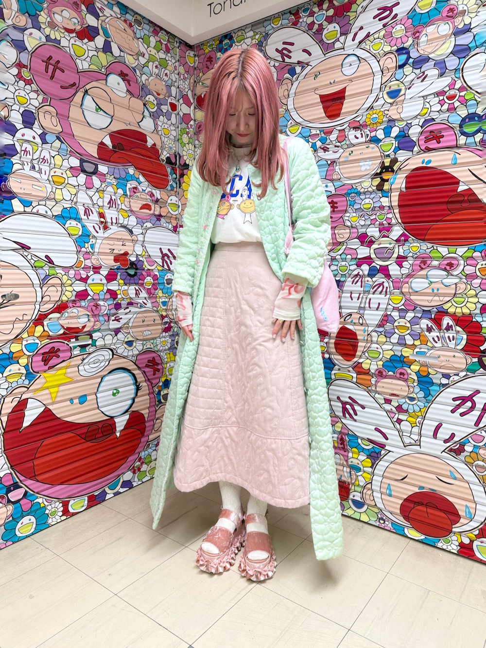 ピンク系のスカート、ピンク系のサンダル、グリーン系のノーカラーコートを着用したレディースの春コーディネートの2枚目の写真