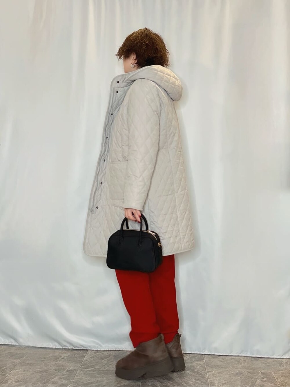 ベージュ系のその他アウター、グレー系のニット/セーター、レッド系のその他パンツを着用したレディースの冬コーディネートの2枚目の写真