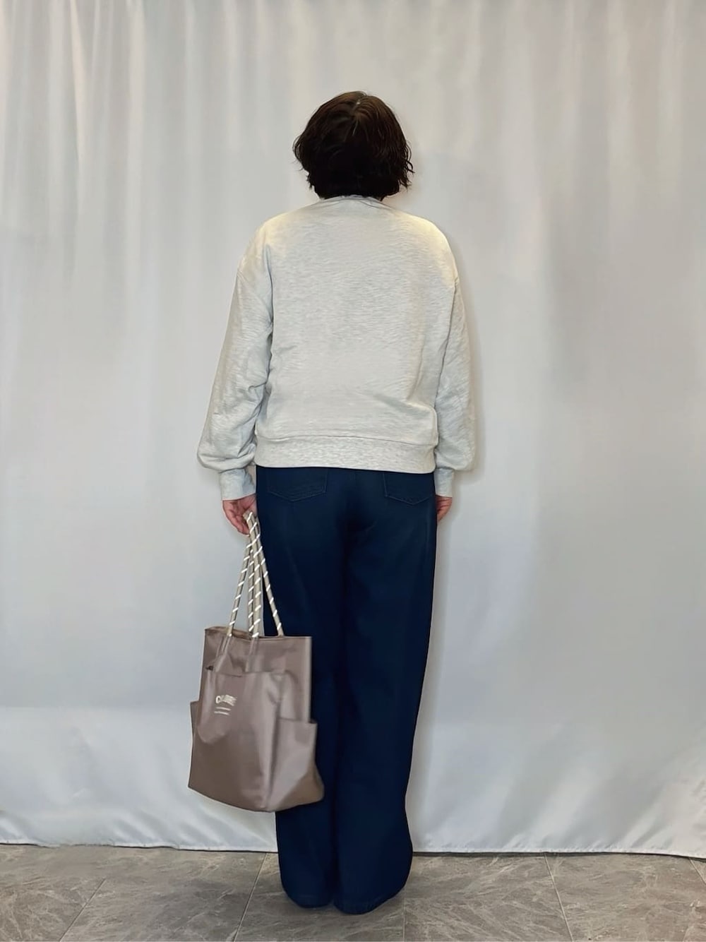 グレー系のスウェット、レッド系のパンプス、ベージュ系のトートバッグを着用したレディースの冬コーディネートの3枚目の写真