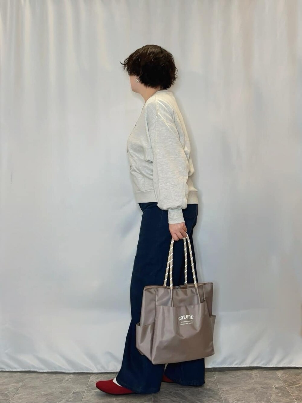 グレー系のスウェット、レッド系のパンプス、ベージュ系のトートバッグを着用したレディースの冬コーディネートの2枚目の写真